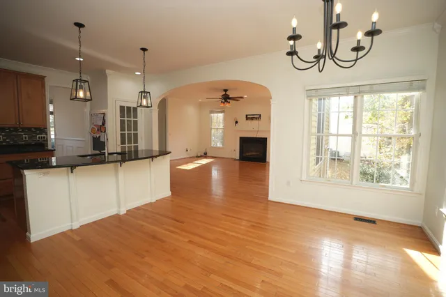 a large white kitchen with granite countertop a stove a sink dishwasher and a fireplace with wooden floor
