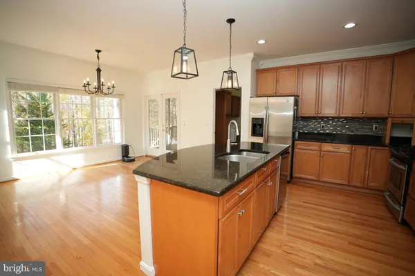 a kitchen with stainless steel appliances granite countertop a sink a stove and a wooden floors
