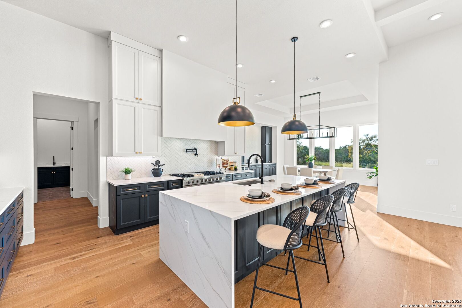 1202 Cielo Rio Drive Pipe Creek, TX 78063 - Photo 11 of 54 a kitchen with stainless steel appliances granite countertop a stove a sink a oven a dining table and chairs with wooden floor