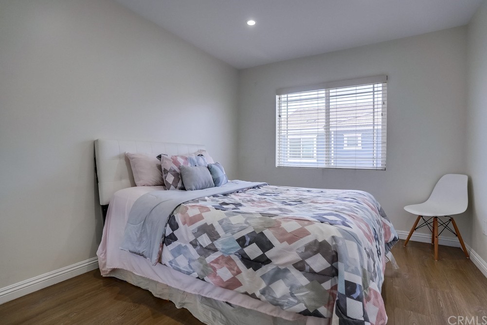 9559 Firestone Boulevard, Unit D Downey, CA 90241 - Photo 24 of 24 a bedroom with a bed and a chair with wooden floor
