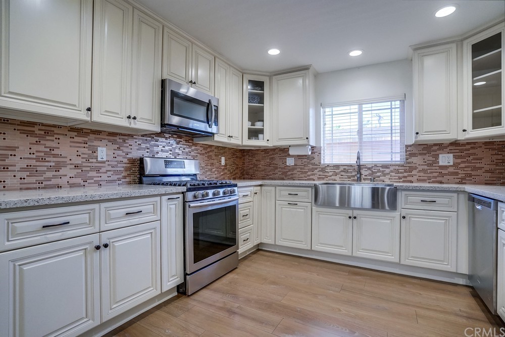 9559 Firestone Boulevard, Unit D Downey, CA 90241 - Photo 7 of 24 a kitchen with granite countertop white cabinets white stainless steel appliances and a sink
