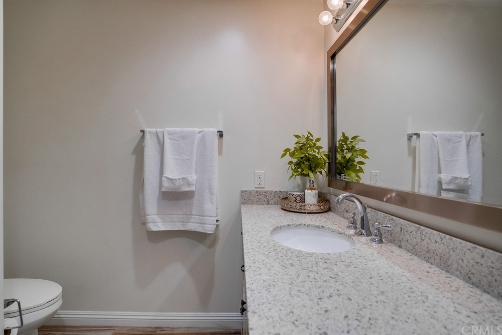 9559 Firestone Boulevard, Unit D Downey, CA 90241 - Photo 9 of 24 a bathroom with a granite countertop sink a toilet and mirror