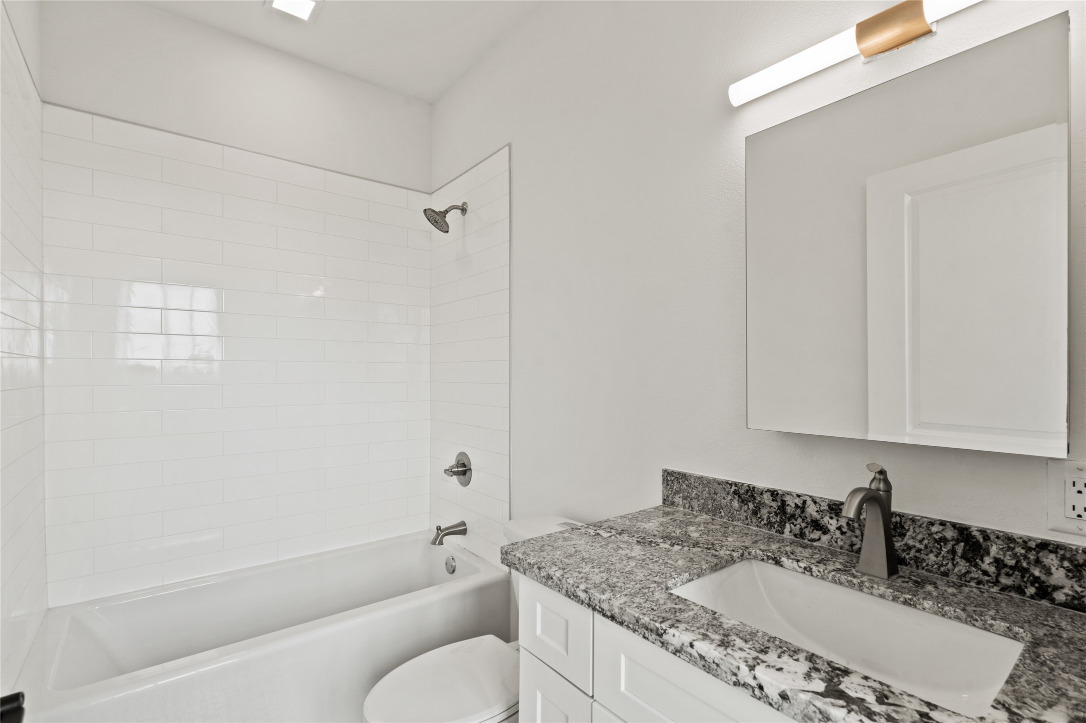 2102 Mechanic Street, Unit 106 Galveston, TX 77550 - Photo 13 of 22 a bathroom with a granite countertop sink a toilet and bathtub