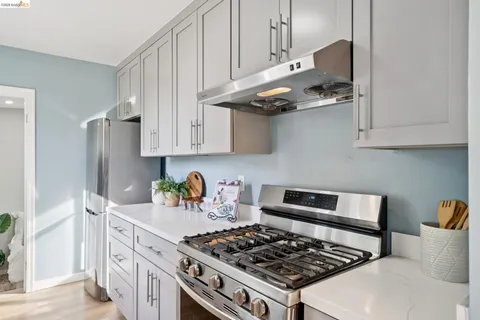 a kitchen with stainless steel appliances granite countertop a stove a refrigerator a sink dishwasher and cabinets with wooden floor