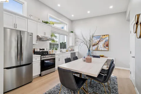 a kitchen with stainless steel appliances granite countertop a refrigerator a stove a sink a dining table and chairs