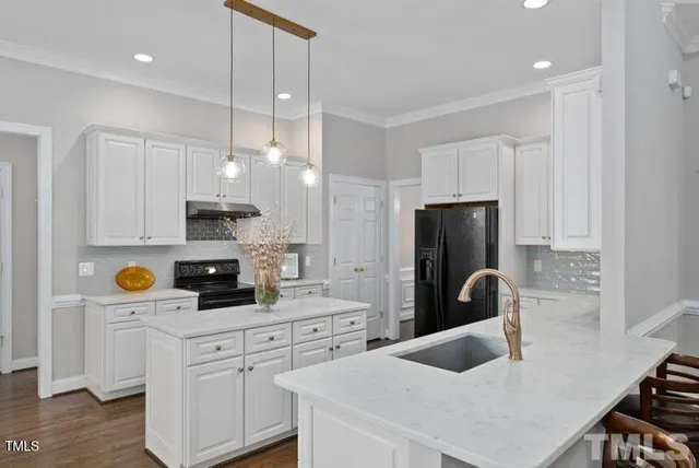 a kitchen with stainless steel appliances a stove a sink a refrigerator a counter space and cabinets