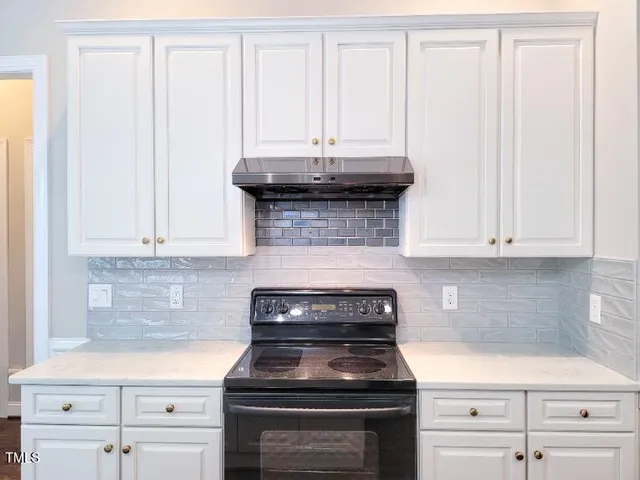 a kitchen with granite countertop white cabinets and black appliances