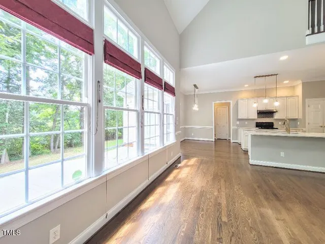 a view of large kitchen with kitchen island wooden floor and stainless steel appliances