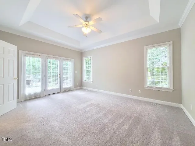 a view of an empty room with chandelier fan and fire place