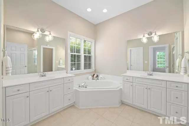 a bathroom with a double vanity sink a mirror a bathtub and shower
