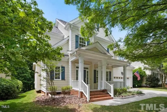 a view of a white house next to a yard with big trees