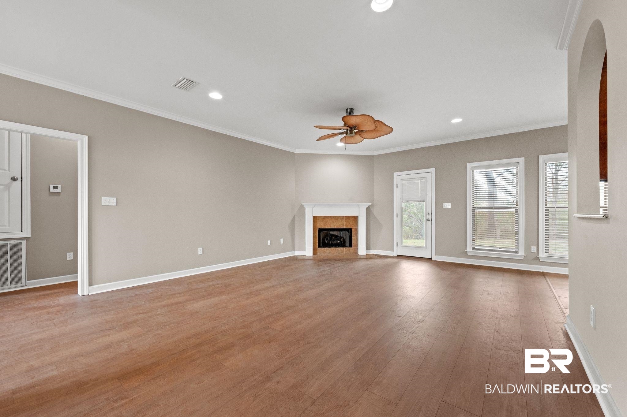 9381 Sable Court Daphne, AL 36526 - Photo 10 of 42 Unfurnished living room with baseboards, visible vents, ceiling fan, a premium fireplace, and wood finished floors