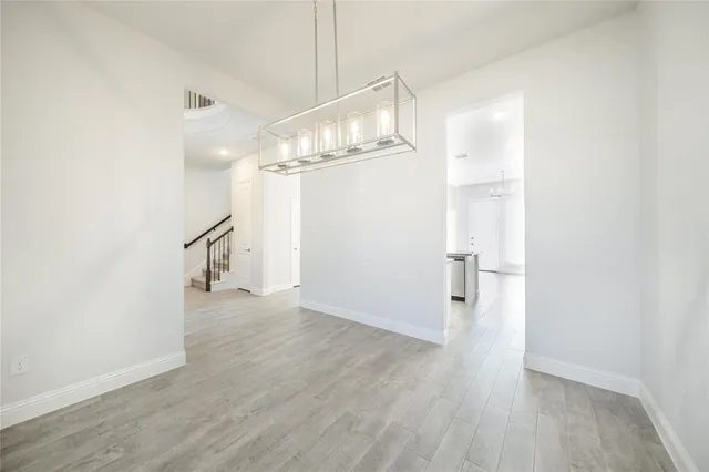 a view of an empty room with wooden floor and a ceiling fan