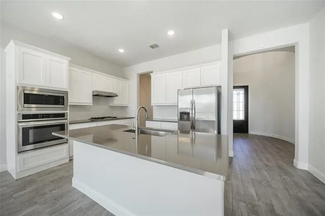 a kitchen with stainless steel appliances granite countertop a refrigerator a stove and a microwave