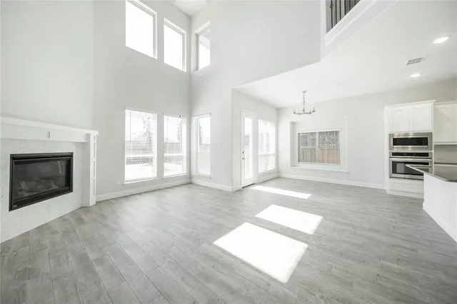 a view of an empty room with wooden floor and a fireplace