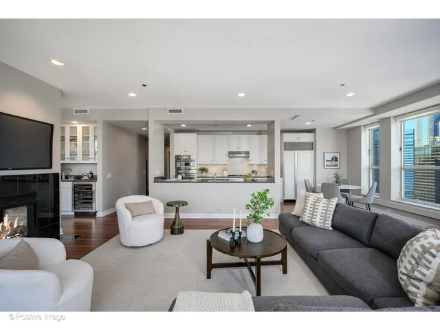 a open kitchen with stainless steel appliances granite countertop a sink dishwasher a stove and white countertops with wooden floor