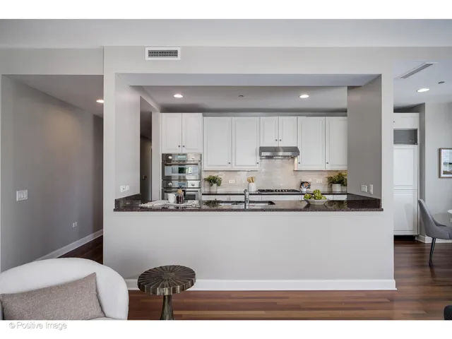 a kitchen with stainless steel appliances granite countertop a sink and a white cabinets