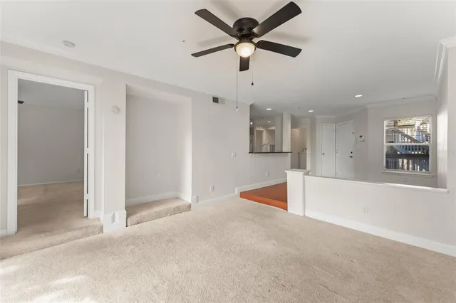 a view of an empty room with window and a kitchen