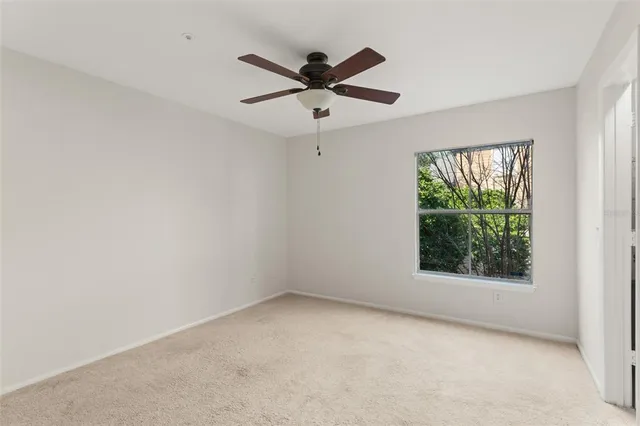 an empty room with windows and ceiling fan