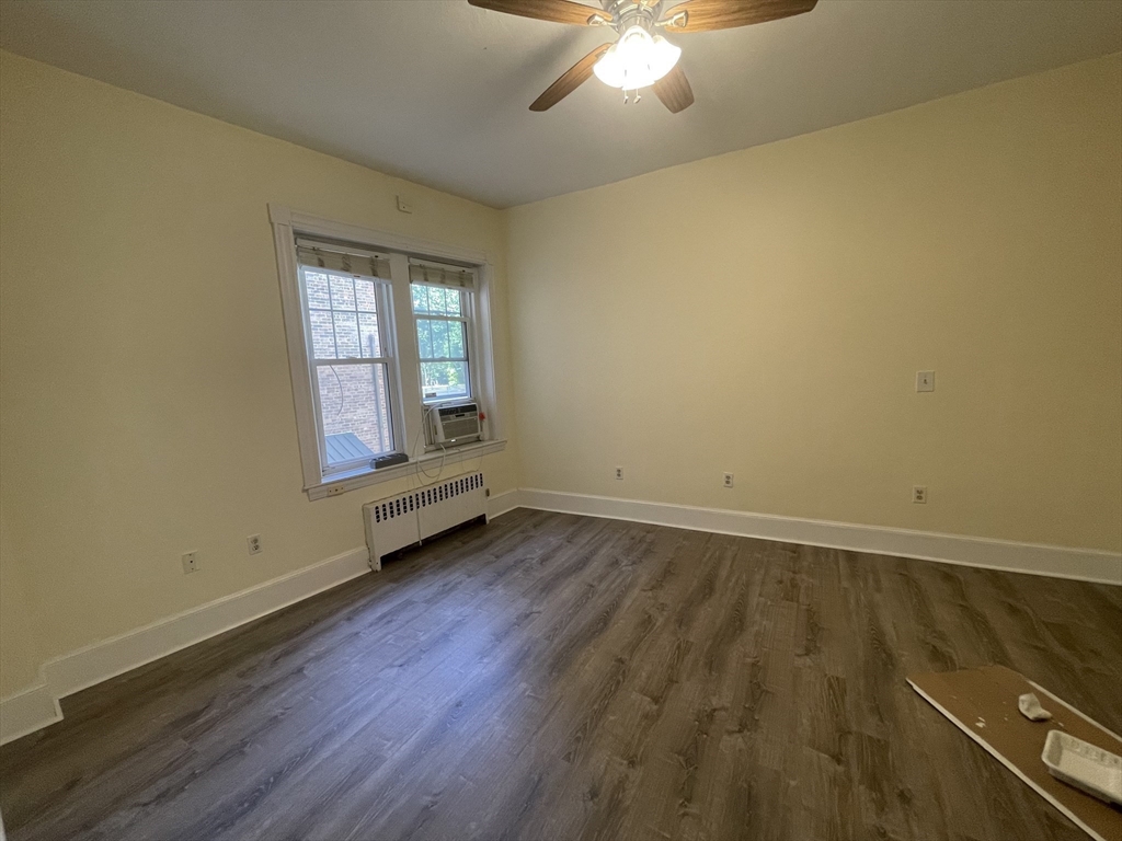 96 St Paul Street, Unit 2 Brookline, MA 02446 - Photo 11 of 14 an empty room with wooden floor chandelier fan and windows