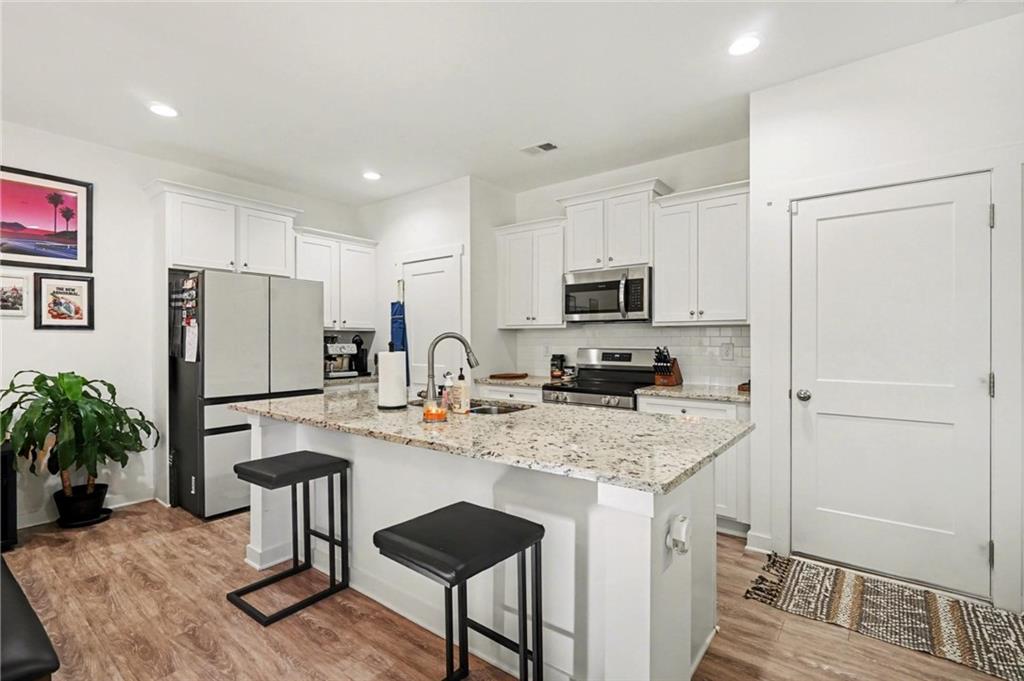 31 Breckens Way Statham, GA 30666 - Photo 11 of 24 a kitchen with stainless steel appliances granite countertop a refrigerator a stove a sink a dining table and chairs with wooden floor