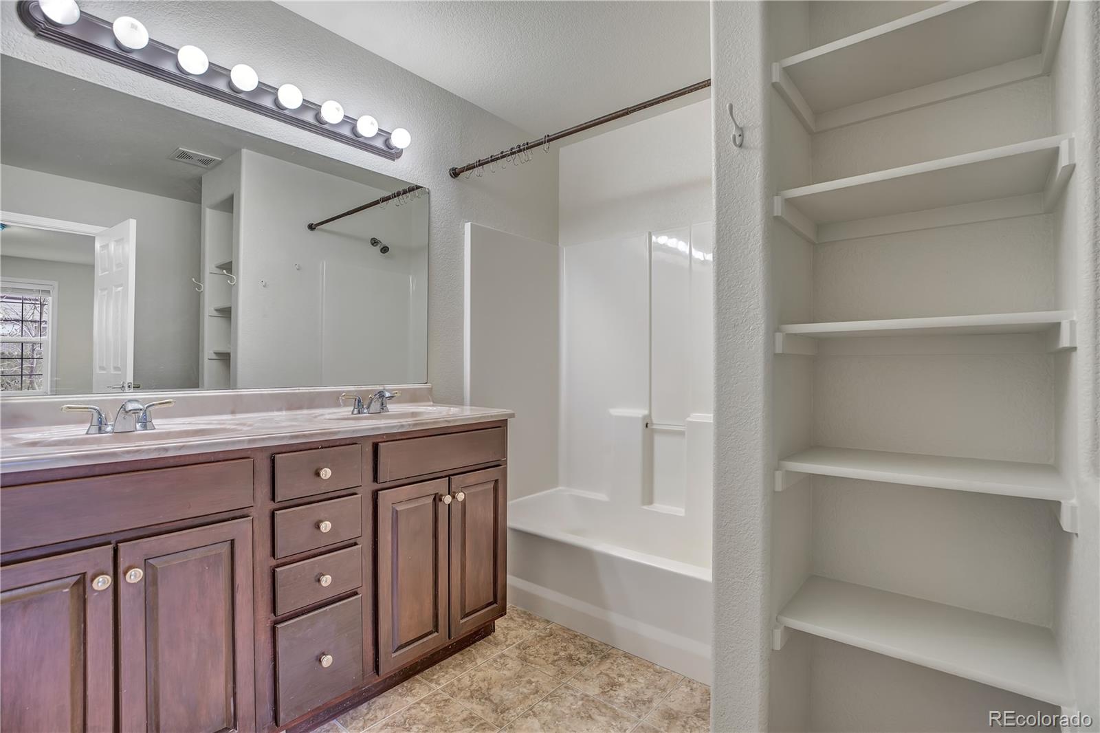 4505 Simms Court Wheat Ridge, CO 80033 - Photo 21 of 37 a bathroom with a granite countertop sink mirror and a bathtub