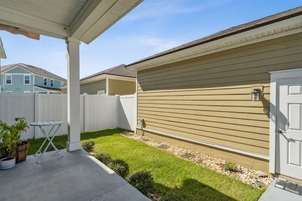 a view of a white house next to a yard with potted plants