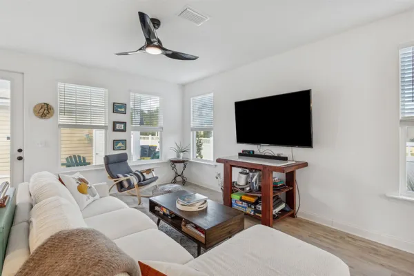 a living room with furniture kitchen view and a wooden floor