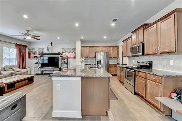 a kitchen with stainless steel appliances kitchen island granite countertop a stove top oven a sink dishwasher a dining table and chairs with wooden floor