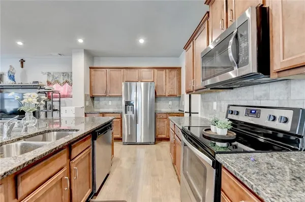 a kitchen with stainless steel appliances granite countertop a sink stove and refrigerator
