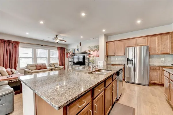 a kitchen with stainless steel appliances granite countertop table chairs sink refrigerator and microwave