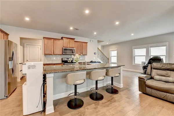 a living room with stainless steel appliances furniture and a kitchen view