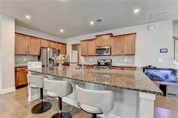 a kitchen with granite countertop kitchen island stainless steel appliances a sink a stove a refrigerator cabinets and a center island