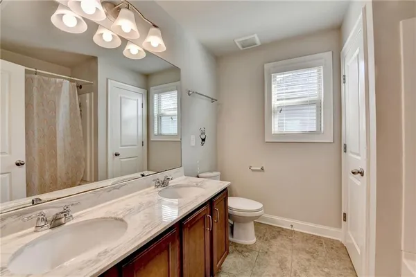 a bathroom with a granite countertop sink a toilet and a mirror