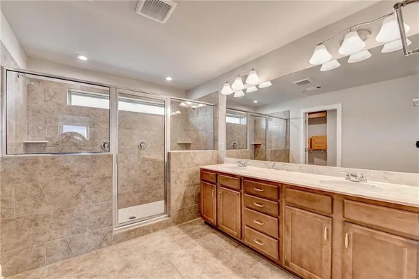 a spacious bathroom with a shower a sink and mirror