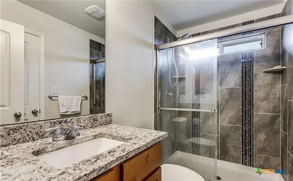 a bathroom with a granite countertop sink mirror and toilet