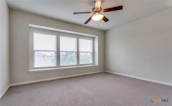 an empty room with a ceiling fan and windows