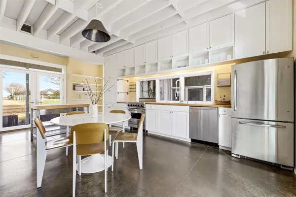 a kitchen with stainless steel appliances granite countertop a stove a refrigerator a dining table and chairs with wooden floor