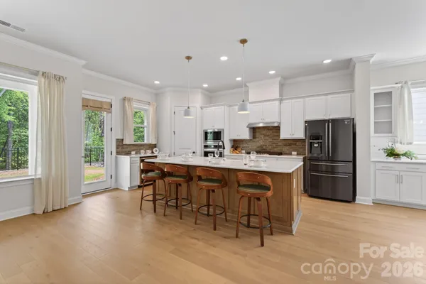 a kitchen with stainless steel appliances granite countertop a stove a refrigerator a sink a dining table and chairs with wooden floor