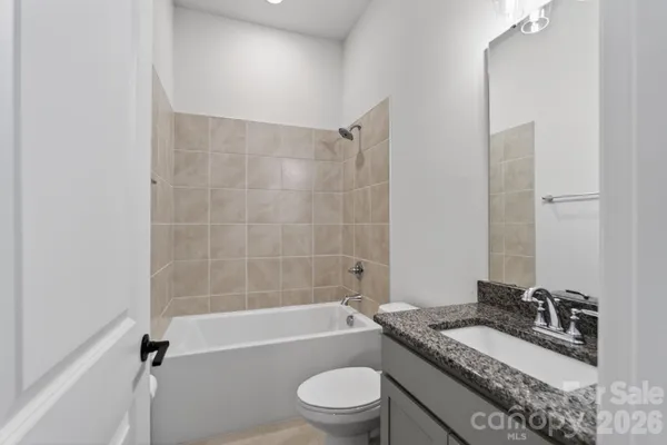 a bathroom with a granite countertop sink toilet a mirror and shower