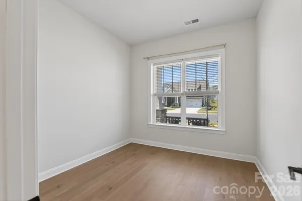 an empty room with wooden floor and windows