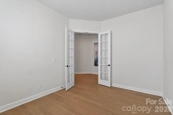 a view of an empty room with wooden floor and closet