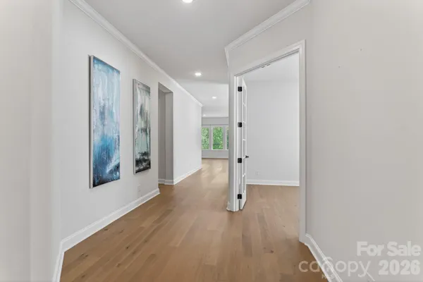a view of a hallway with wooden floor and a bathroom