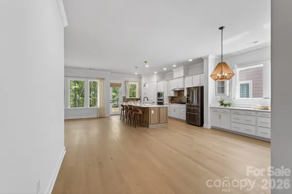 a open kitchen with granite countertop a stove a sink dishwasher a refrigerator and white cabinets with wooden floor
