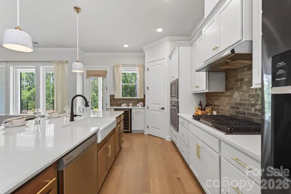 a open kitchen with stainless steel appliances granite countertop sink stove and white cabinets with wooden floor
