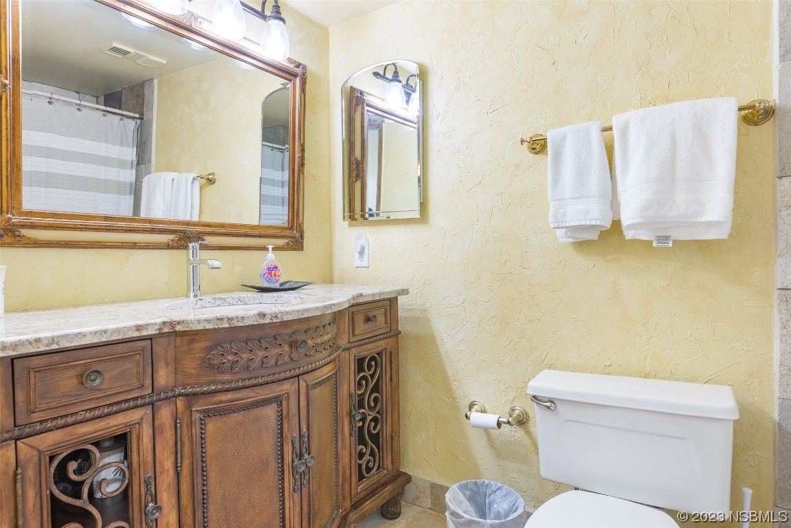 4745 South Atlantic Avenue, Unit 4030 Ponce Inlet, FL 32127 - Photo 11 of 47 a bathroom with a granite countertop toilet sink and mirror