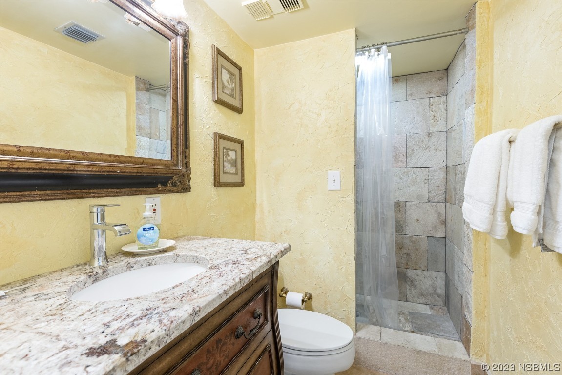 4745 South Atlantic Avenue, Unit 4030 Ponce Inlet, FL 32127 - Photo 14 of 47 a bathroom with a granite countertop sink a toilet and shower