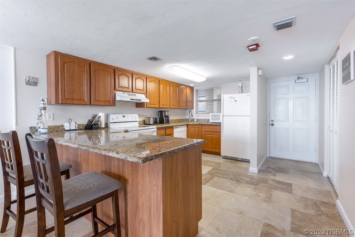 4745 South Atlantic Avenue, Unit 4030 Ponce Inlet, FL 32127 - Photo 19 of 47 a kitchen with granite countertop a table chairs microwave and refrigerator