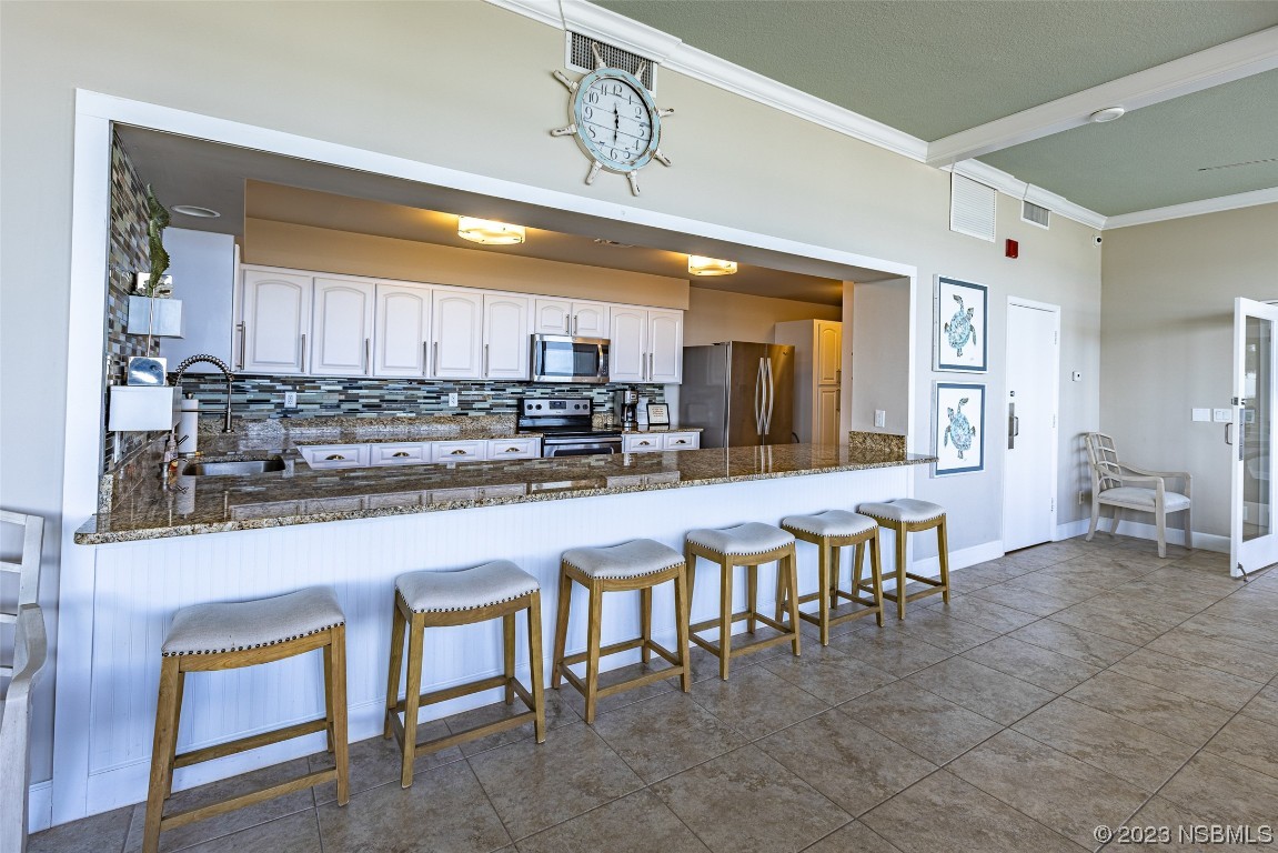 4745 South Atlantic Avenue, Unit 4030 Ponce Inlet, FL 32127 - Photo 43 of 47 a kitchen with table chairs sink and cabinets