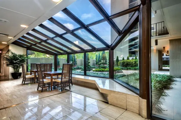 a view of a patio with table and chairs potted plants and floor to ceiling window